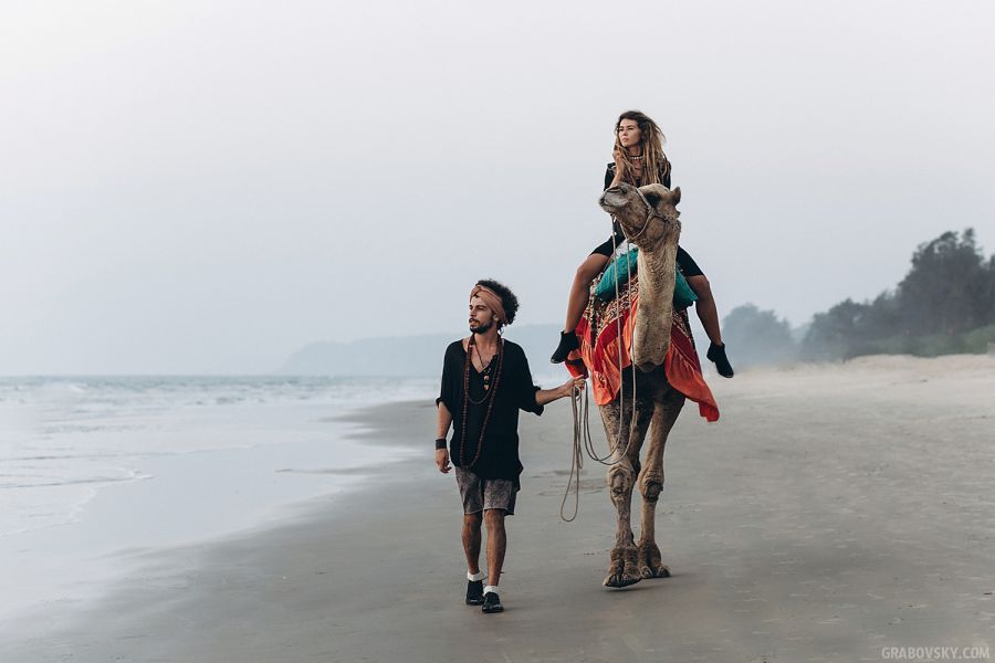 Пара гуляет по берегу на верблюде